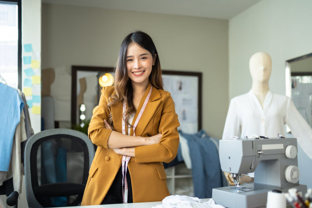 年轻的亚洲女企业家时装设计师与笔记本电脑在家里办公室工作。图片下载