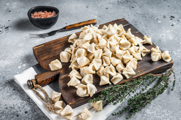 生的曼蒂饺子在木板上与草药，生的食物。灰色的背景。俯视图图片下载