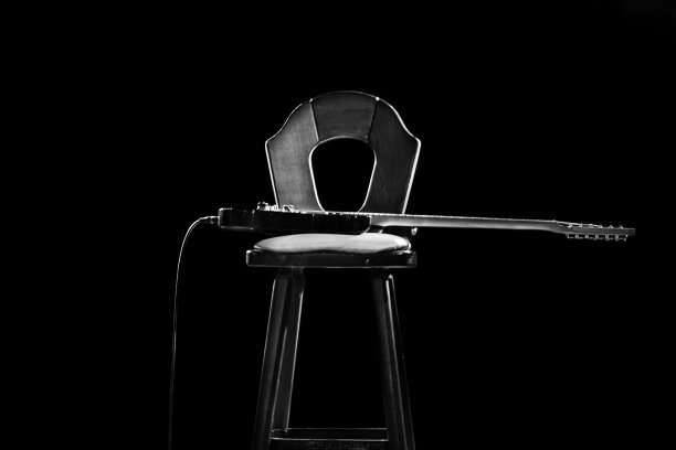一把电吉他放在椅子上的灰度镜头图片下载