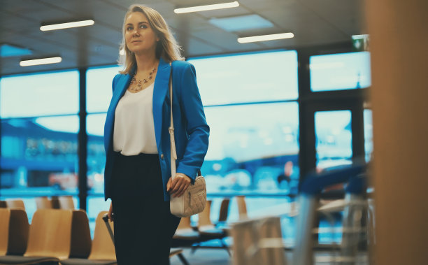 女人带着行李箱走在机场候机楼。图片下载