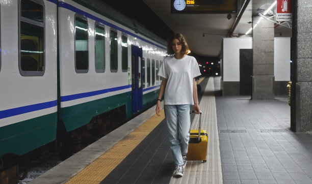 一个十几岁的女孩穿过车站走向火车。图片下载