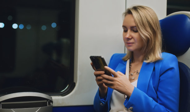 一名身穿西装、带着手机的女子乘火车旅行。图片下载