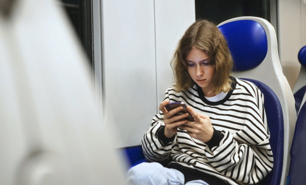十几岁的女孩带着智能手机在火车里旅行。图片下载