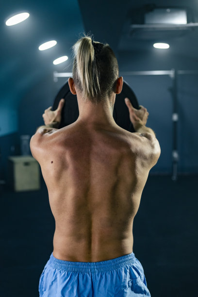 肌肉男子在健身房持有重量板的后视图。图片下载