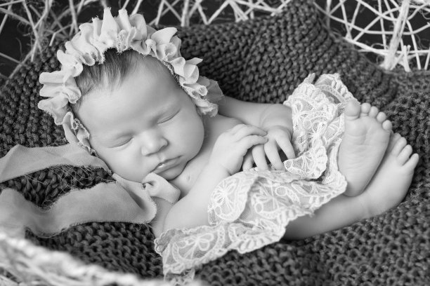 可爱的新生女婴睡在篮子里。深棕色背景。图片下载