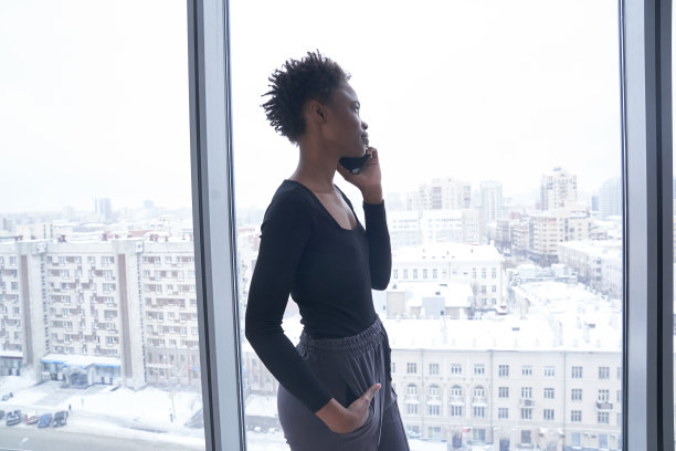 一名穿着运动服的年轻黑人女子一边打电话一边看向别处。一个留着短发的不满意的年轻女人。有复制空间的生活方式照片。高质量照片图片下载