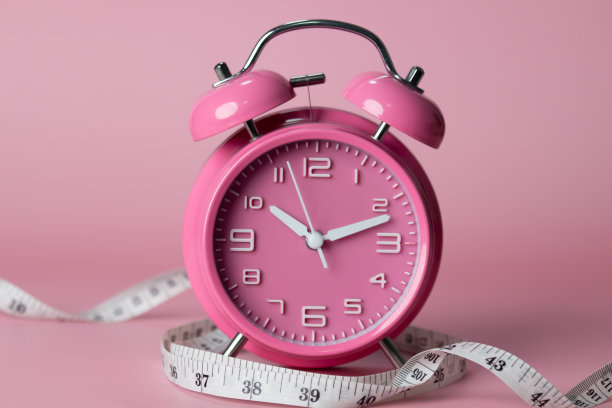 粉色闹钟，带卷尺。健康的生活方式，减肥。图片下载
