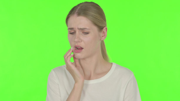 年轻女子牙痛在绿色背景图片下载