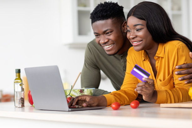 黑人配偶在厨房使用笔记本电脑和信用卡，在网上订购杂货图片下载