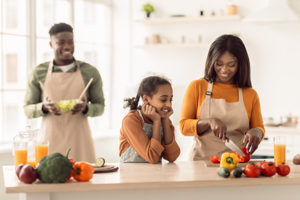 快乐的非裔美国家庭一起做沙拉在厨房做饭图片下载