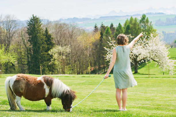 户外肖像快乐的年轻女子玩小马，农场度假图片下载