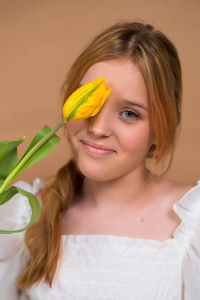 一个穿着白色连衣裙的女人用一朵郁金香闭上了眼睛。3月8日。妇女节。女性的节日。妈妈的节日。一束花。
米色背景上带花的女孩图片下载