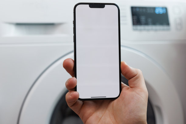 使用手机应用程序手动操作智能洗衣机的特写。将洗衣机与智能手机连接。智能家居和物联网概念图片下载