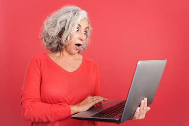 惊讶的成熟女子站在使用笔记本电脑图片下载