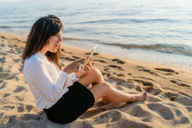 一名年轻女子在海滩上的平板电脑上看到的东西让她感到惊讶图片下载