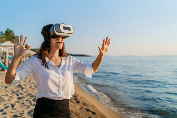 海滩上戴着虚拟现实耳机的年轻女子图片下载
