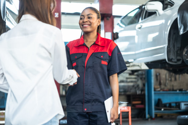 领取车钥匙的女人。身着制服的年轻非洲女汽车修理工正在把车钥匙还给客户，两人都面带微笑。图片下载