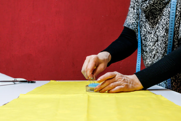 一位女裁缝正在车间里用针准备材料。图片下载