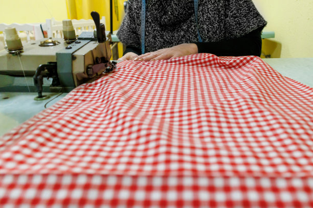 一个女裁缝用缝纫机做衣服的特写照片。图片下载