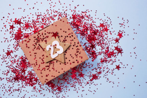 给祖国保卫者节的贺卡。白色，金色，红色星星，一个礼盒，浅蓝色背景上的数字23。假期是2月23日。图片下载