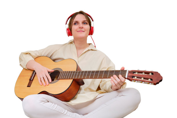 快乐的女人坐在家里的客厅里弹吉他，孤立在白色背景上图片下载