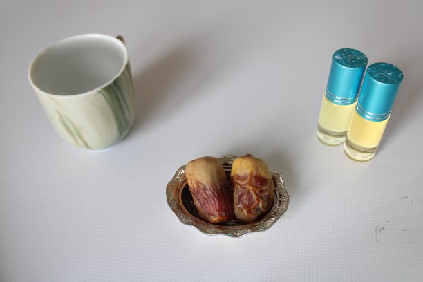 白色背景上的麦地那蜜枣、渗渗泉水、黑色念珠和香精油。斋月主题照片。图片下载