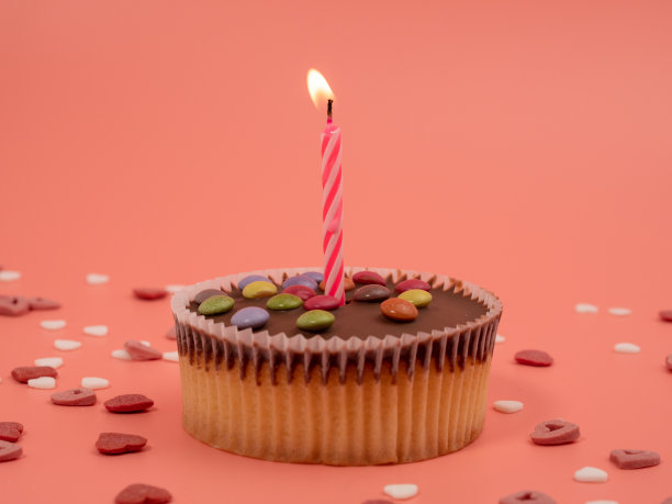 粉色背景上有蜡烛的松饼。假日松饼。图片下载