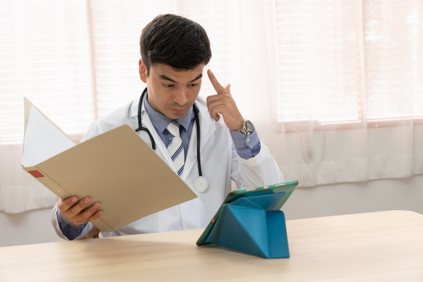 医生使用平板电脑在线视频会议向患者询问家中头痛症状。图片下载