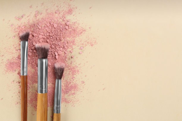 化妆刷和分散的眼影在米色背景上，平铺。文本空间图片下载