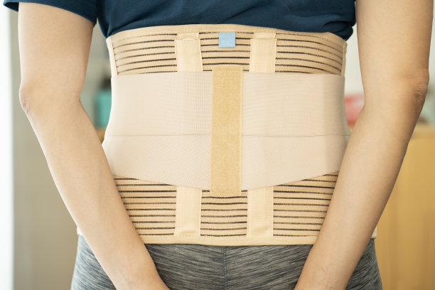 年轻的亚洲女性穿着背部支撑，保护她的背部，药物和健康的概念图片下载