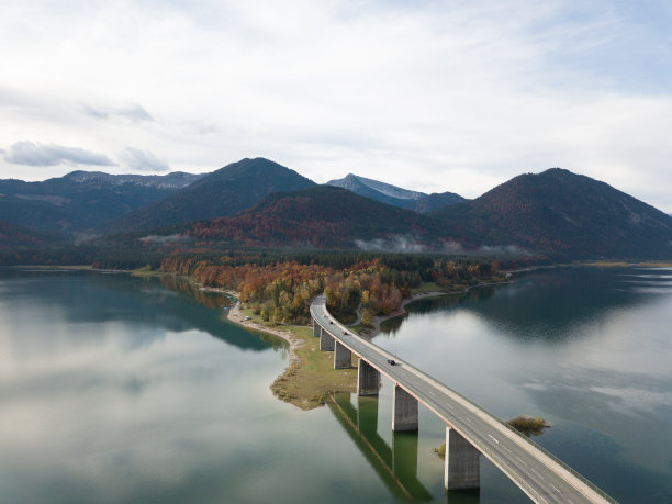 桥上的汽车，公路旅行和电动汽车。这张令人惊叹的照片捕捉到了Sylvensteinsee的美丽，这是一个风景如画的湖泊，位于德国巴伐利亚州的秋天。图片下载