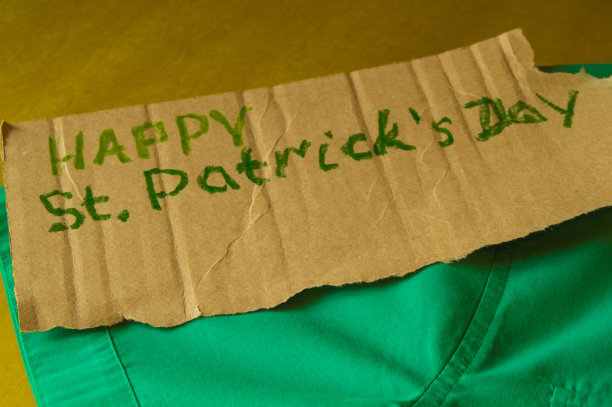 为庆祝圣帕特里克节做准备的概念，绿色衬衫躺在桌子上，文字，金色背景图片下载