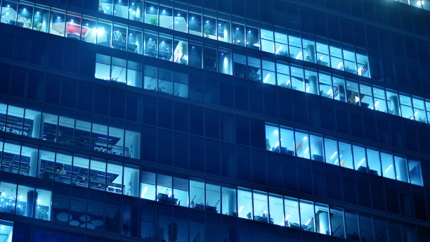 图案的办公楼窗户在夜间照明。图片下载