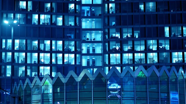 图案的办公楼窗户在夜间照明。图片下载