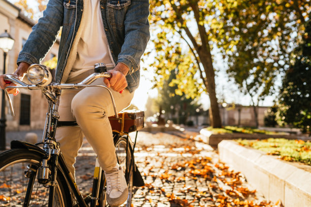 一个穿着牛仔夹克的年轻人骑着他的复古经典自行车的裁剪图像。图片下载