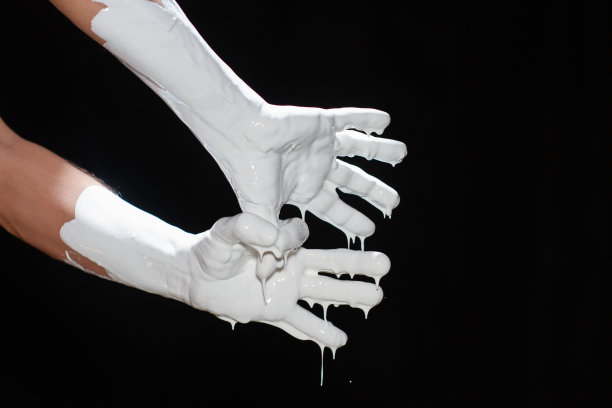 一个男人的手在黑色背景上涂着白色颜料。图片下载