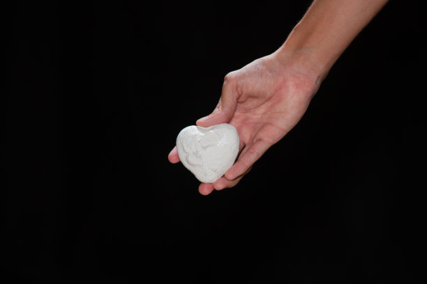 一个男人的手在黑色背景上涂着白色颜料。图片下载