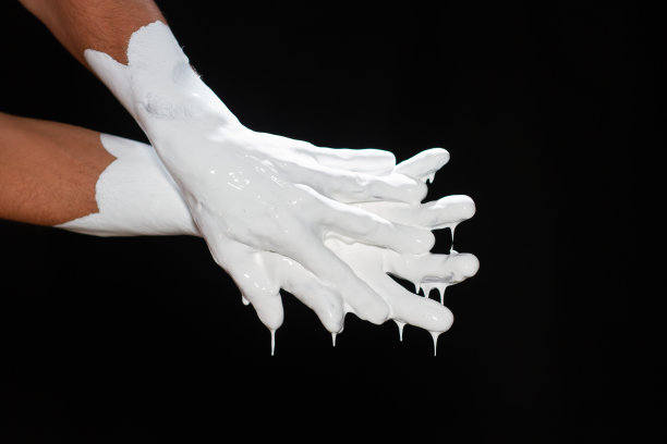 一个男人的手在黑色背景上涂着白色颜料。图片下载