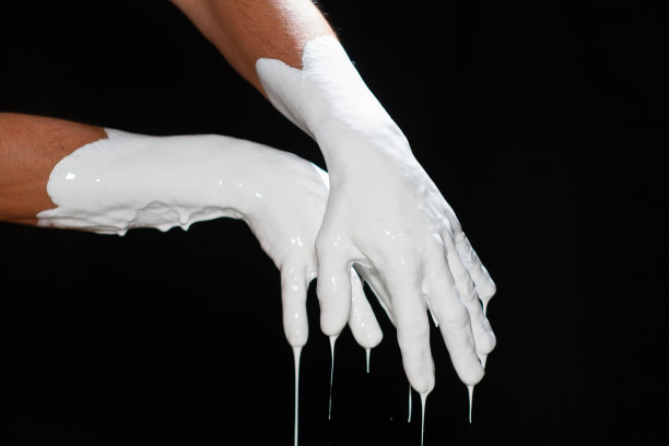 一个男人的手在黑色背景上涂着白色颜料。图片下载