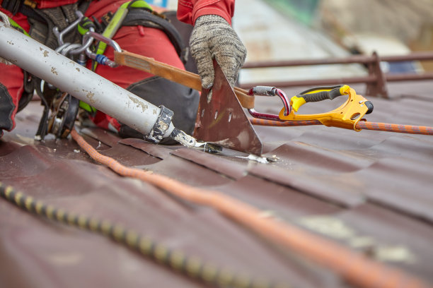 屋顶修复。用绳子到屋顶。一个男人在修理一座大厦的屋顶。图片下载