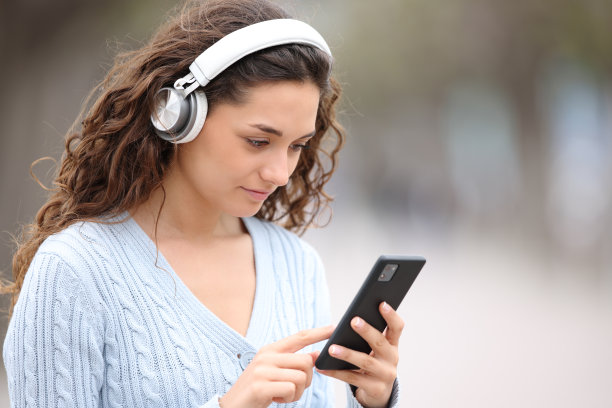 戴着耳机的女子在户外查看手机图片下载