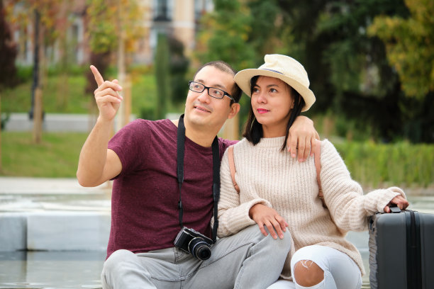 多种族的游客夫妇指指点点，坐下来休息。图片下载