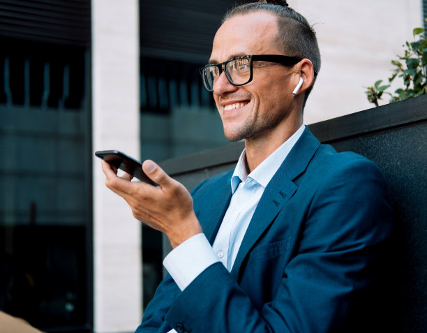 年轻时髦的男人在一个现代化的办公室旁边用免提电话说话。图片下载