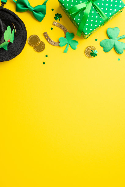 圣帕特里克节的概念。俯视图垂直照片绿色礼物盒妖精帽子金币马蹄形蝴蝶结三叶草和三叶形纸屑孤立的黄色背景与复制空间图片下载