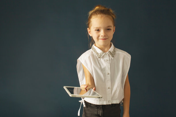 金发女孩与平板电脑在工作室在深蓝色的背景。孩子图片下载