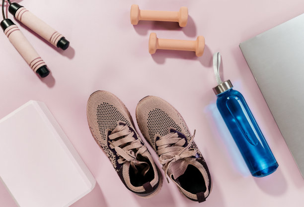 健身、瑜伽配件套装。胸罩，瑜伽用的粉色积木，装水的瓶子，哑铃，运动鞋，跳绳，粉红色背景的笔记本电脑。运动装备，极简的背景。近距离图片下载