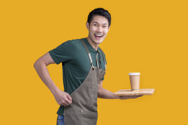 聪明友好的亚洲男眼镜咖啡师小咖啡店老板在围裙的手势欢迎顾客来享受他的咖啡饮料，快乐的亚洲男展示咖啡与微笑和自信的工作室拍摄图片下载