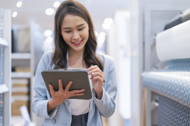 聪明休闲的亚洲女性创业企业家小企业主商业女性微笑手使用平板电脑工作组织库存产品货架检查在陈列室工作室办公室白天背景图片下载