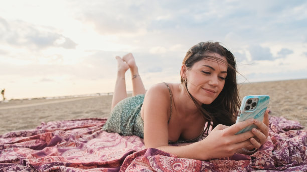年轻女子在海滩上放松，用手机图片下载