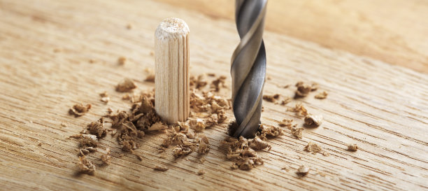 钻头在橡木木板上钻孔，用于木销子。图片下载